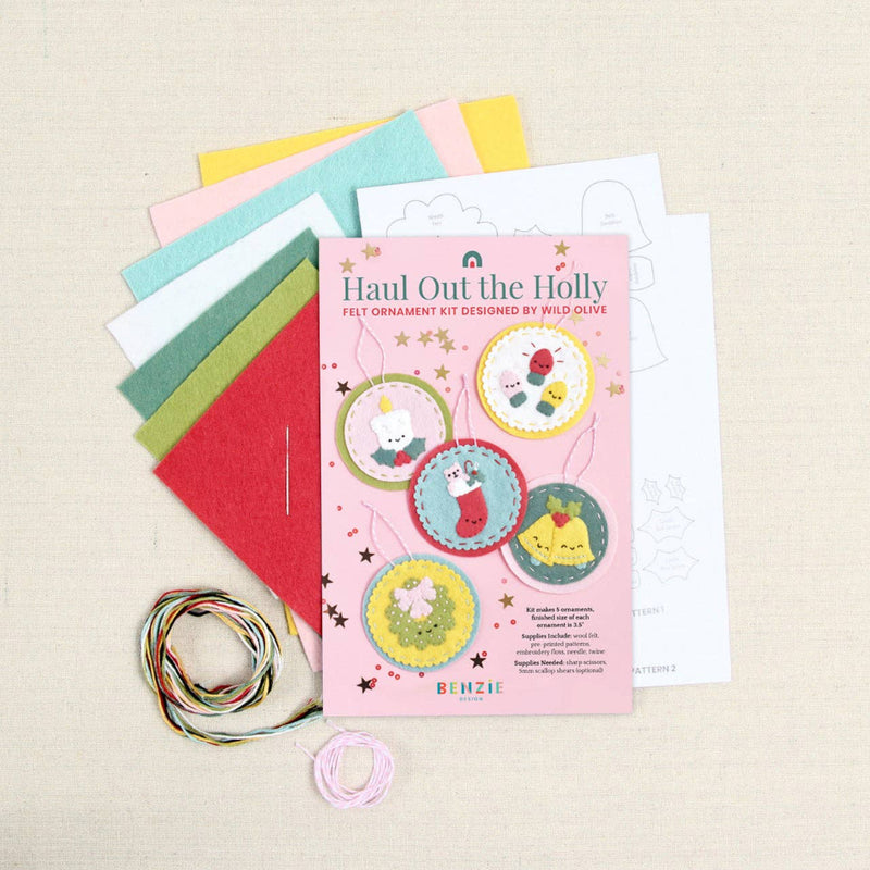 Sheets of felt, pattern, needle, and floss with a "Haul Out the Holidays" label on a white textured background
