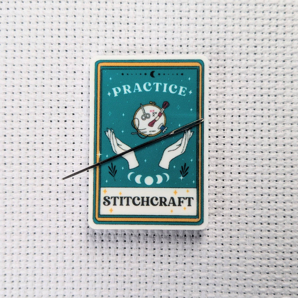 Stitchcraft card with hands holding a needle on a cross-stitched background