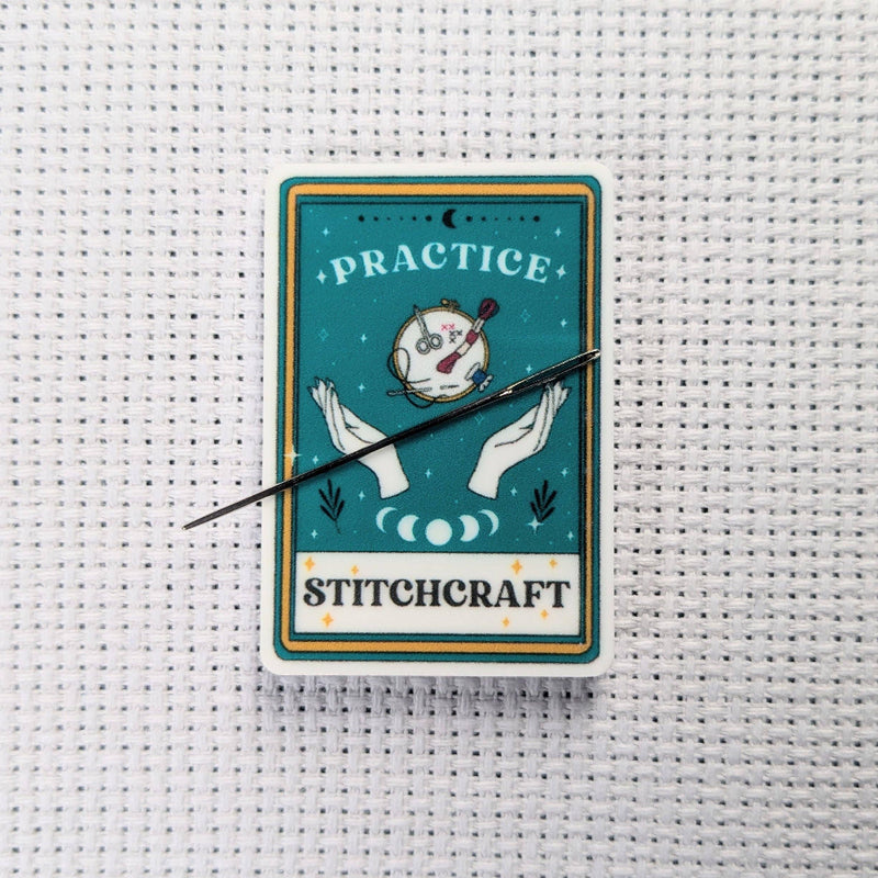 Stitchcraft card with hands holding a needle on a cross-stitched background