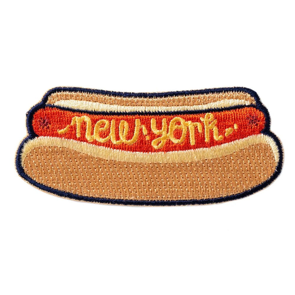 An iron-on patch with a hot dog design, with "New York" written in yellow, against a white background. 