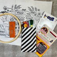 Embroidery kit with hoop, thread, and pattern sheets on a gray surface