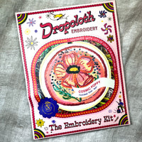 Embroidery kit packaging with 'Dropoloth Embroidery' branding on a textured fabric background.