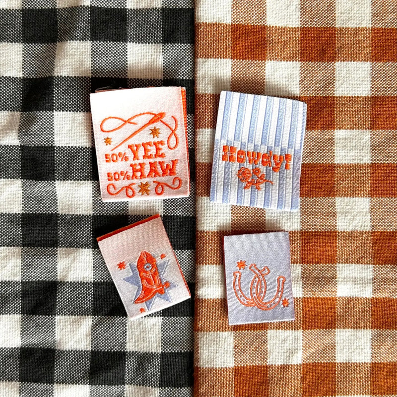 Embroidered labels with a cowboy theme on a checkered fabric background