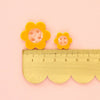 Yellow flower-shaped buttons with a ruler on a pink background