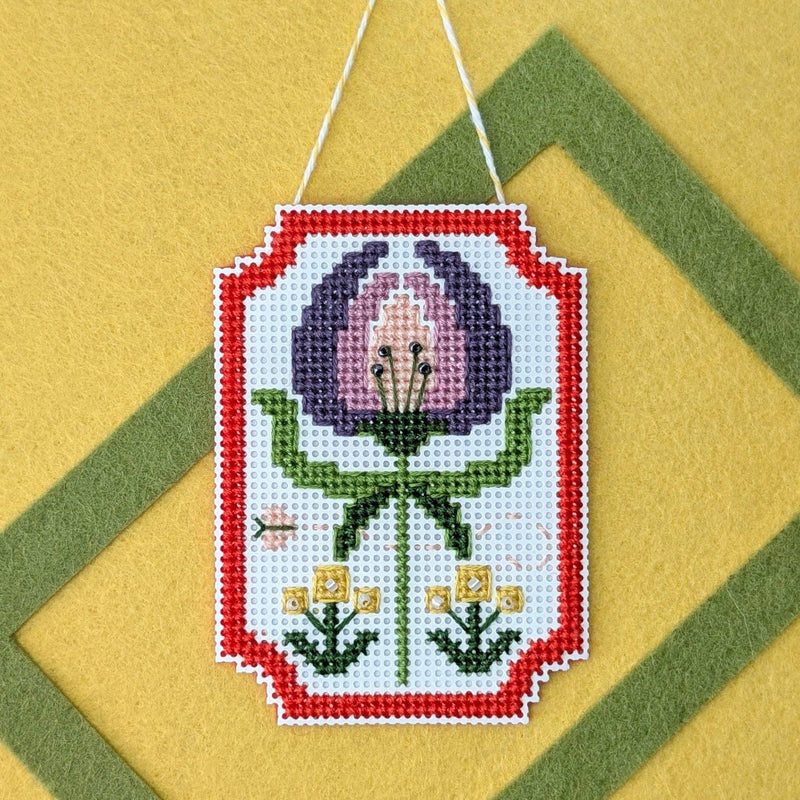 Framed crocus cross stitch on a yellow felt background with a green felt frame