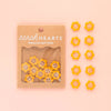 Packaged yellow flower buttons with 'Sarah Hearts' branding on a pink background