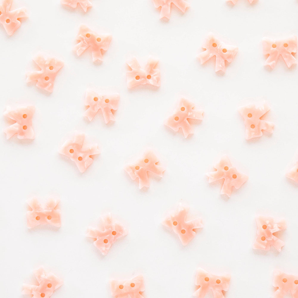 Pattern of small pink bows on a white background