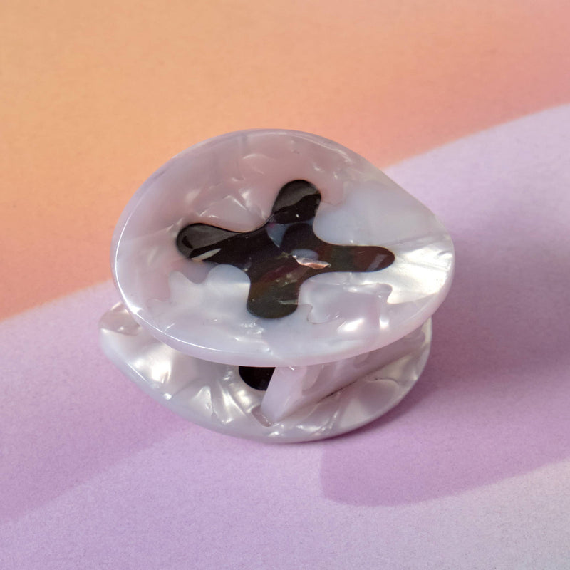 Clear plastic object with a black cross design on a pink background