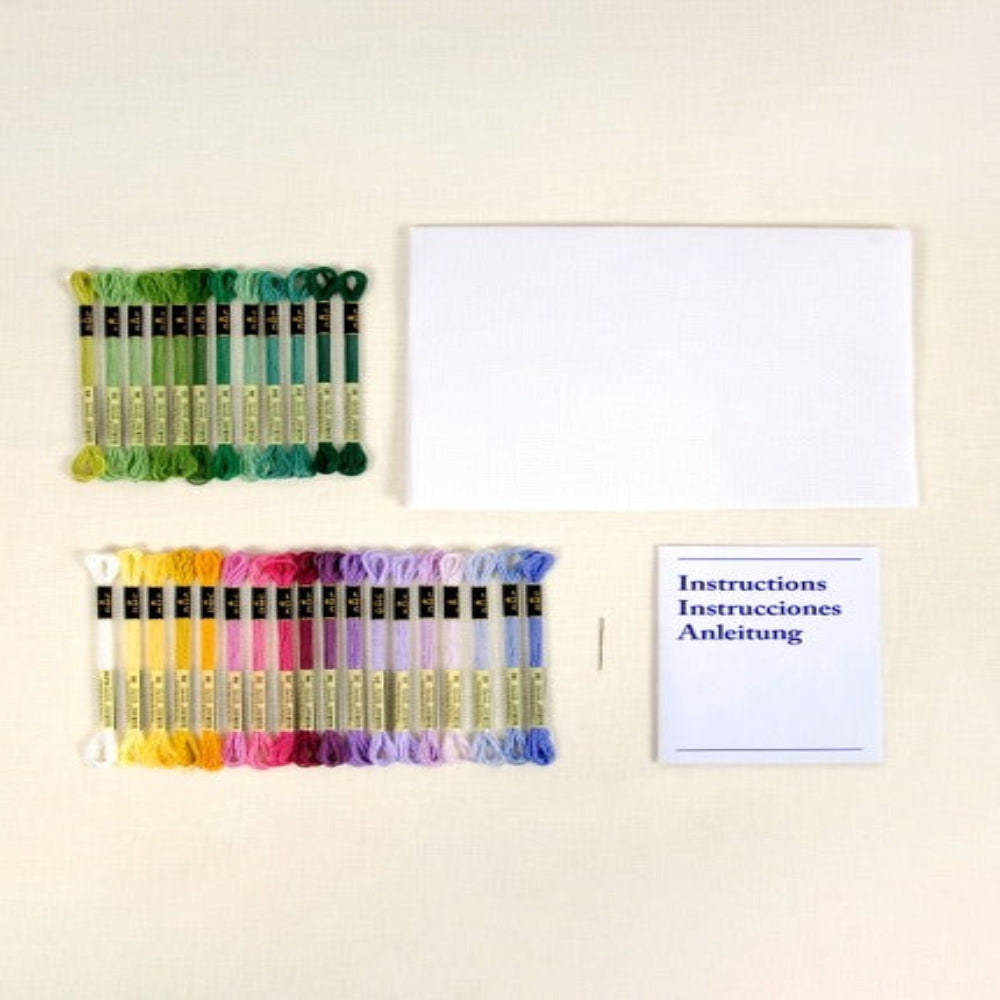 Set of embroidery threads and needles with a set of instructions on a light background