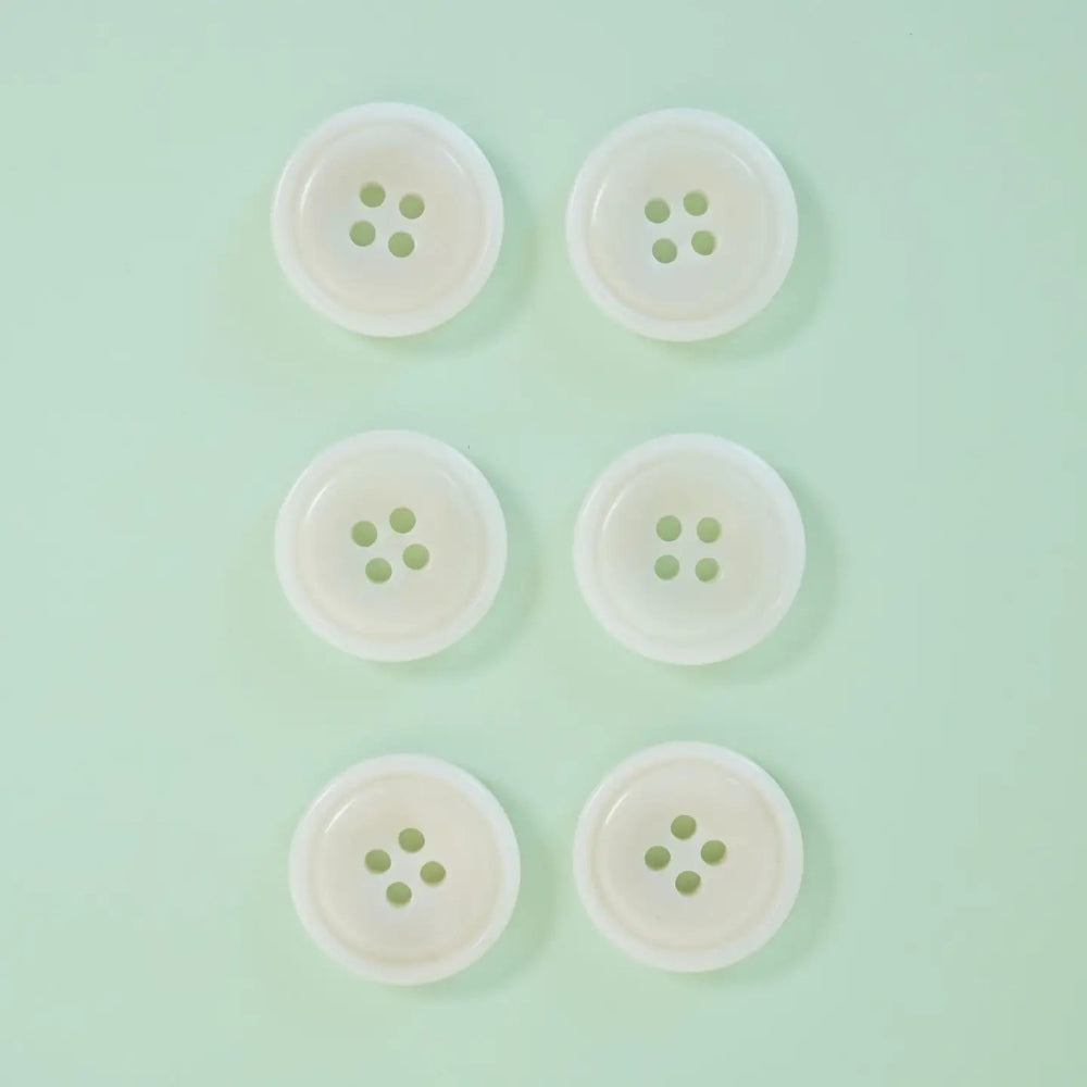 Six white buttons with green centers arranged in two rows on a light green background