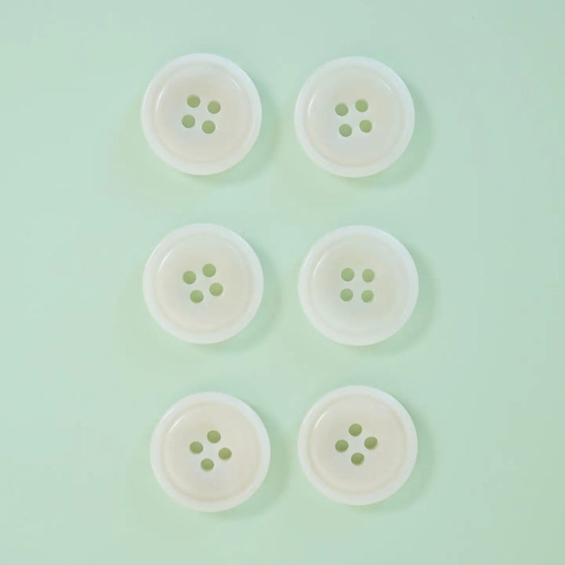 Six white buttons with green centers arranged in two rows on a light green background