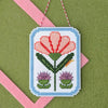 Framed carnation cross stitch on a green felt background with a pink felt frame