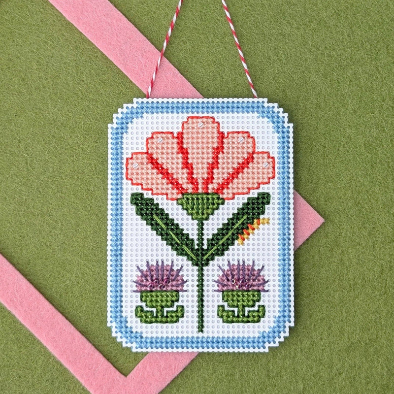 Framed carnation cross stitch on a green felt background with a pink felt frame
