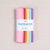 Multicolor shades of felt in pinks, oranges, yellows, blues, and purples with a "Wool Blend Felt" label around them on a textured white background