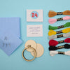 cross stitch kit with threads, hoop, and cards on a blue background