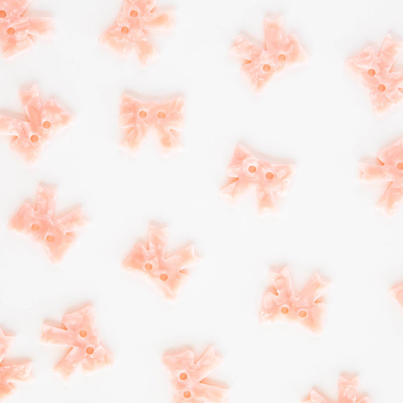Pattern of pink bow shapes on a white background