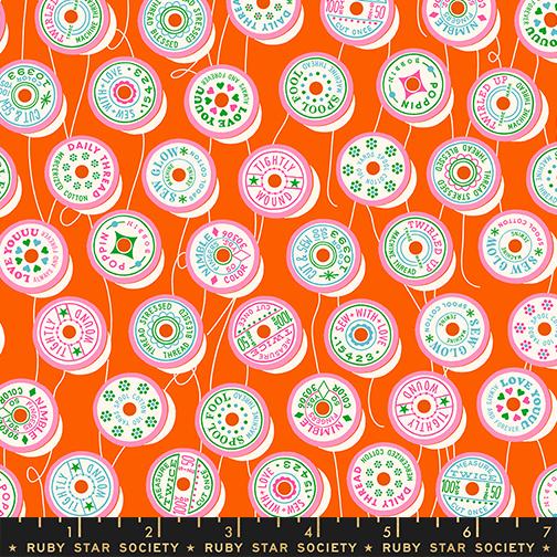 Patterned fabric with colorful spool designs on an orange background, featuring the Ruby Star Society label.