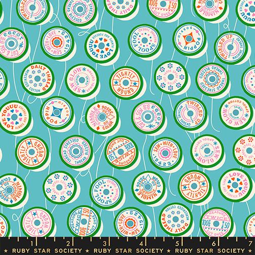 Patterned fabric with colorful spool designs on a blue background, featuring the Ruby Star Society label.