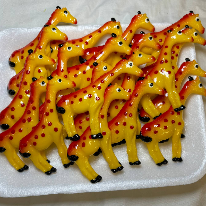 White tray of yellow giraffe magnets with orange spots and black hooves