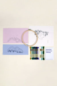Embroidery hoop with thread and pattern cards on a beige background
