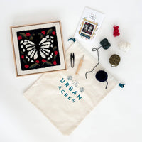 Latch hook kit with completed project, yarn, and tools on a white background