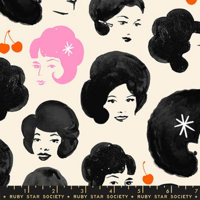 Fabric swatch of black and white drawings of women's faces, an outlying woman drawn in pink is in the upper left. There are red cherries scattered between the women.
