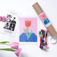 needlepoint kit with red tulip on pink and blue background and embroidery floss 