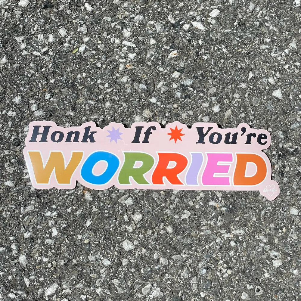 Colorful sticker saying " Honk if You're Worried" on a grey background