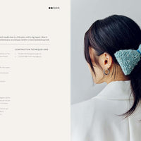 Woman with a blue bow in her hair against a light gray background