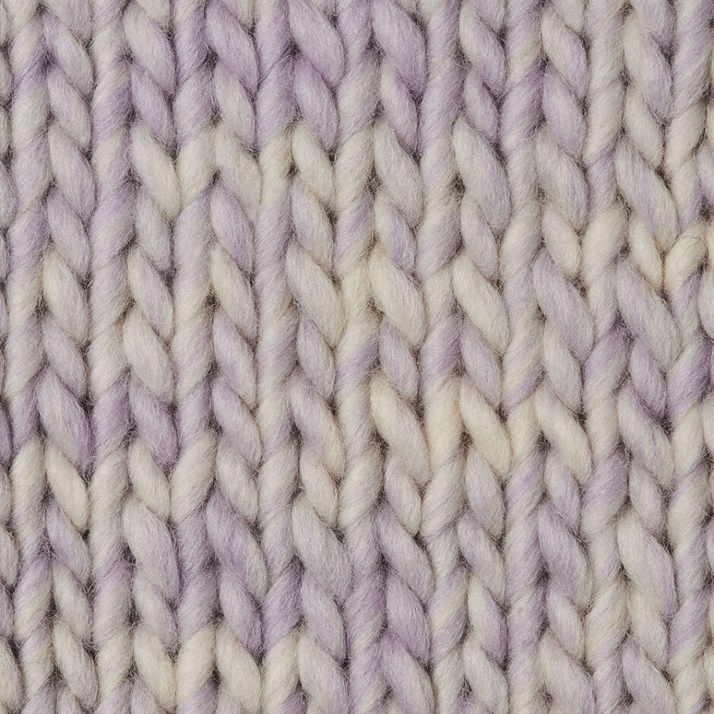Close-up of a chunky knit swatch  in a variegated soft lilac and cream colorway.