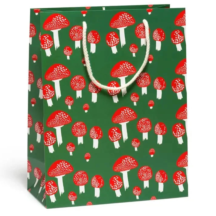 Gift bag with festive red mushrooms on a green background