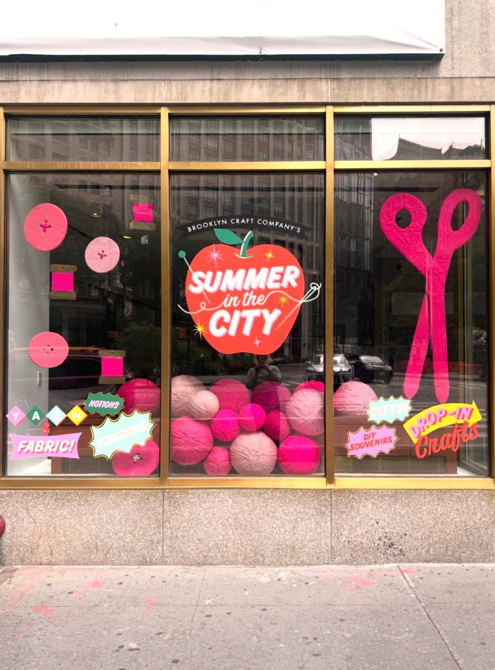 Store window display with 'Summer in the City' theme featuring pink and red decorations.