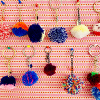 Colorful pom-pom keychains on a pink patterned background