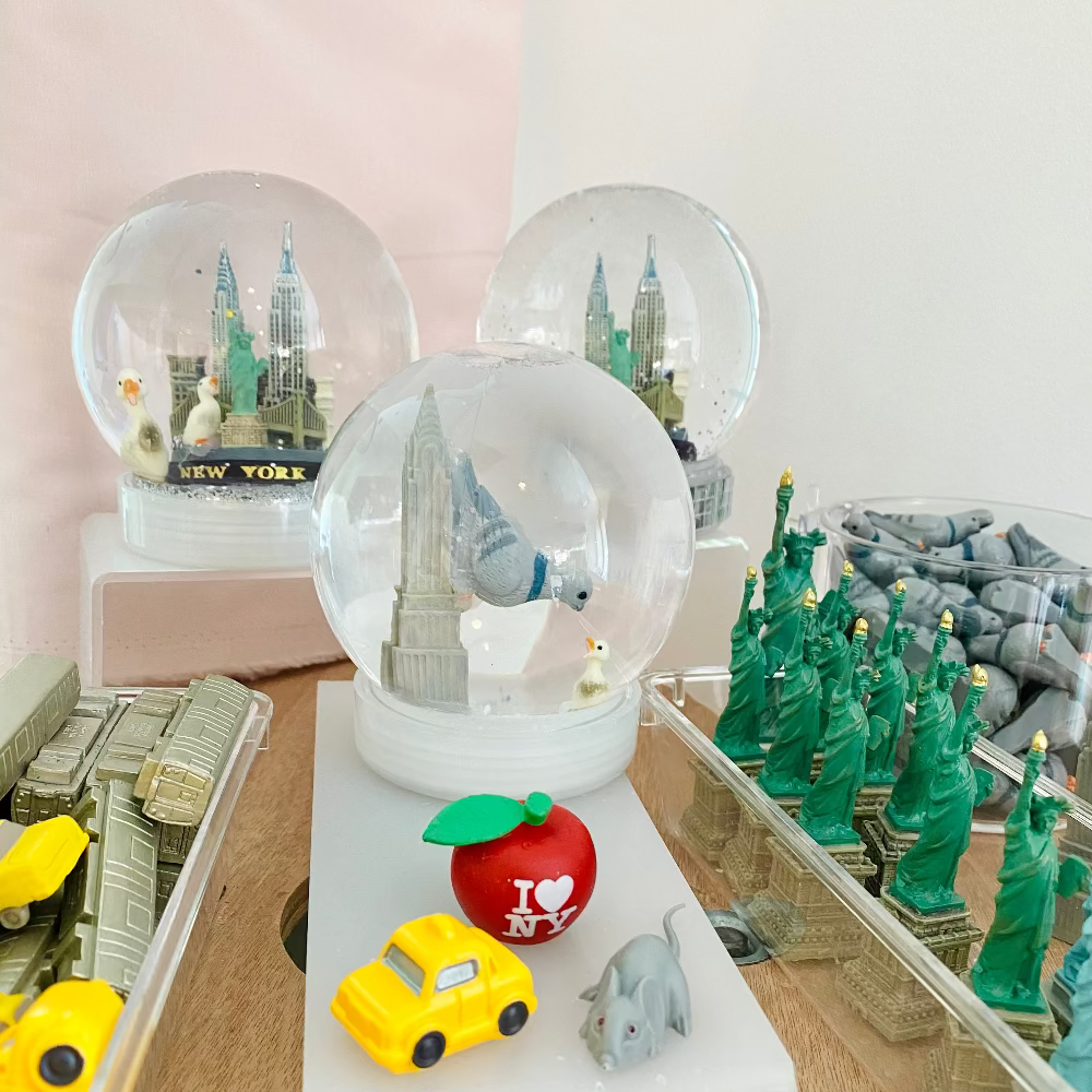 Collection of small models and decorative items including snow globes and toy cars on a table.