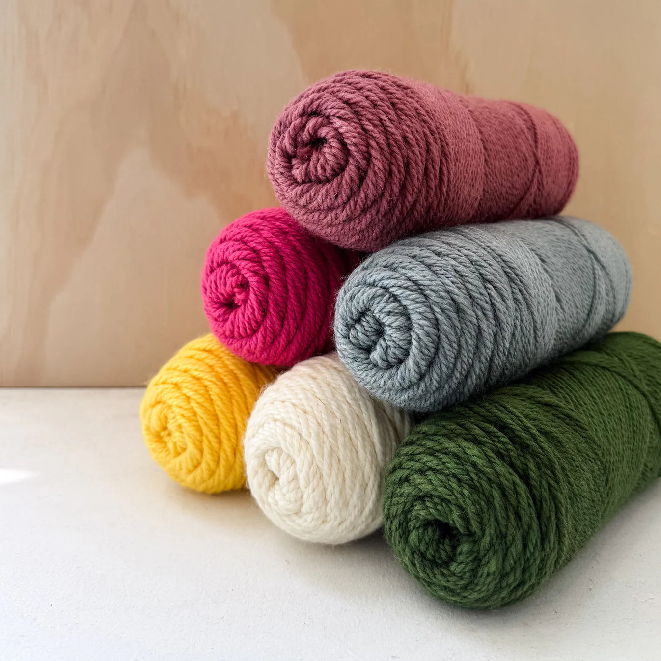 Stack of colorful yarn rolls on a light surface with a wooden background