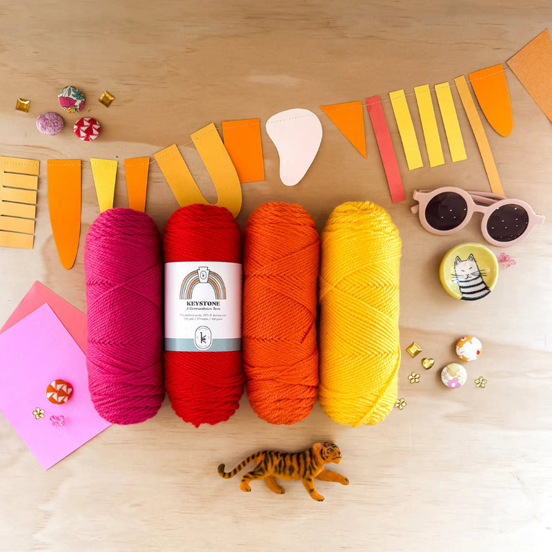 Colorful yarn skeins on a wooden surface with decorative items.