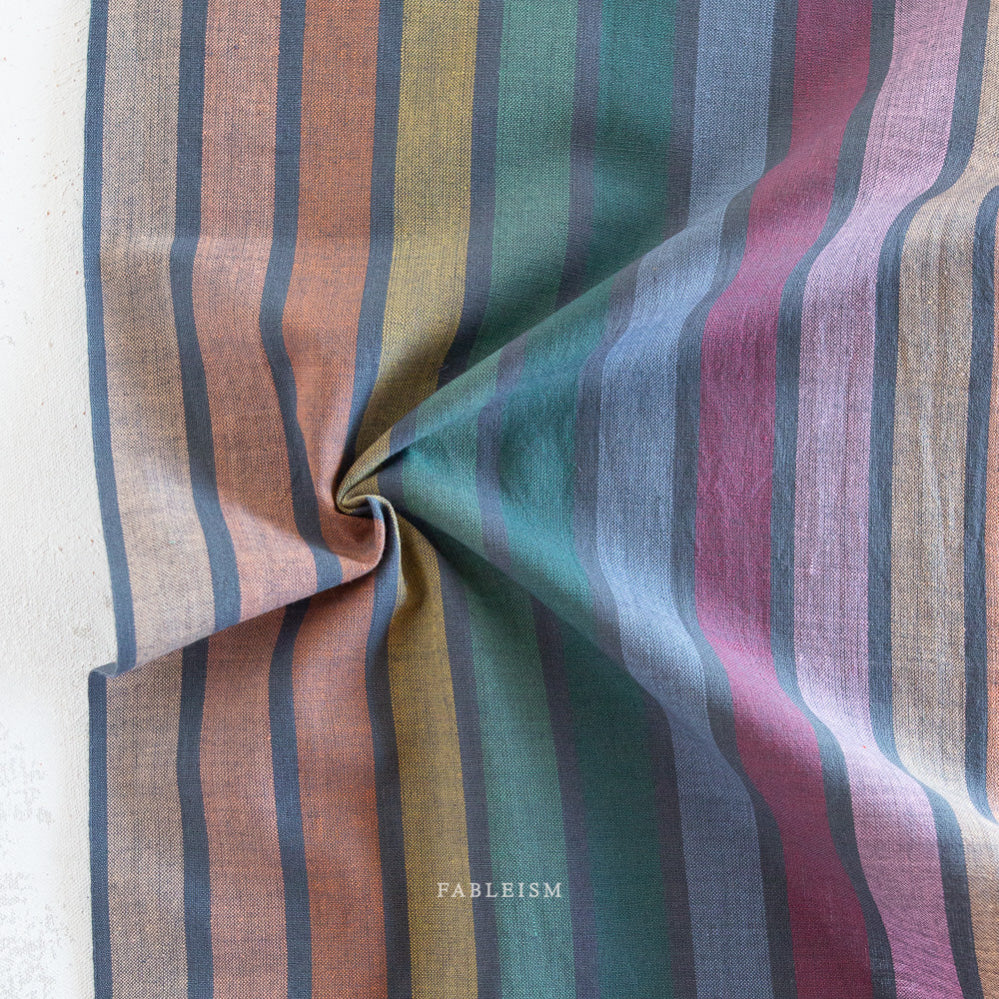 Striped fabric with multicolor pattern on a dark background, branded 'Fableism'.