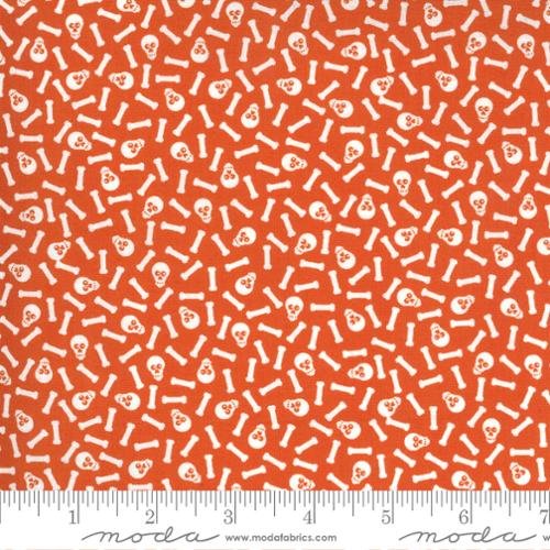 Fabric with white skull and bone pattern on an orange background, featuring a ruler at the bottom.