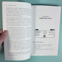 Open book with yarn label on a teal background