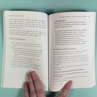 Open book with text on a teal background, held open by a hand.