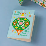 Blue card with green floral ornament that reads Have Yourself A Merry Little Christmas
