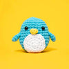 Crocheted penguin toy on a yellow background