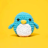 Crocheted penguin toy on a yellow background
