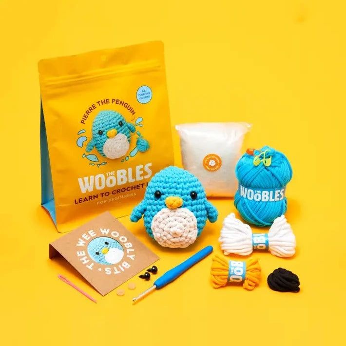 Crochet kit with blue penguin themed items on a yellow background