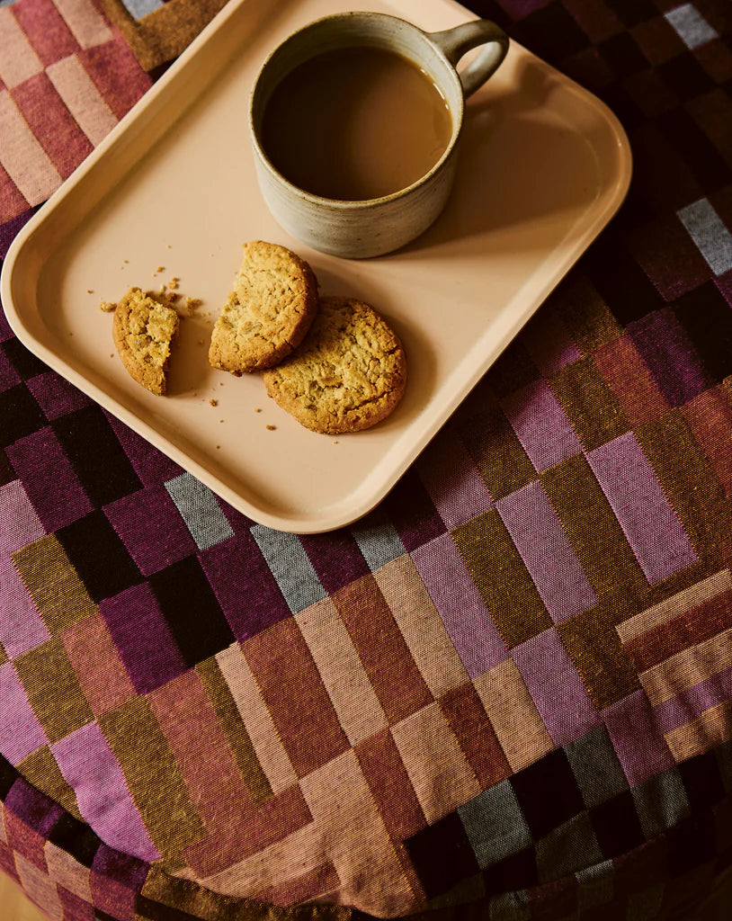 Tray with cookies and a cup of coffee on a patterned tablecloth