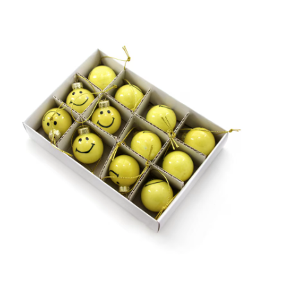 Box of yellow Christmas balls with smiley faces on a white background