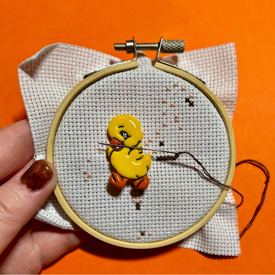 cute handmade yellow duck needle minder on a cross stitch project