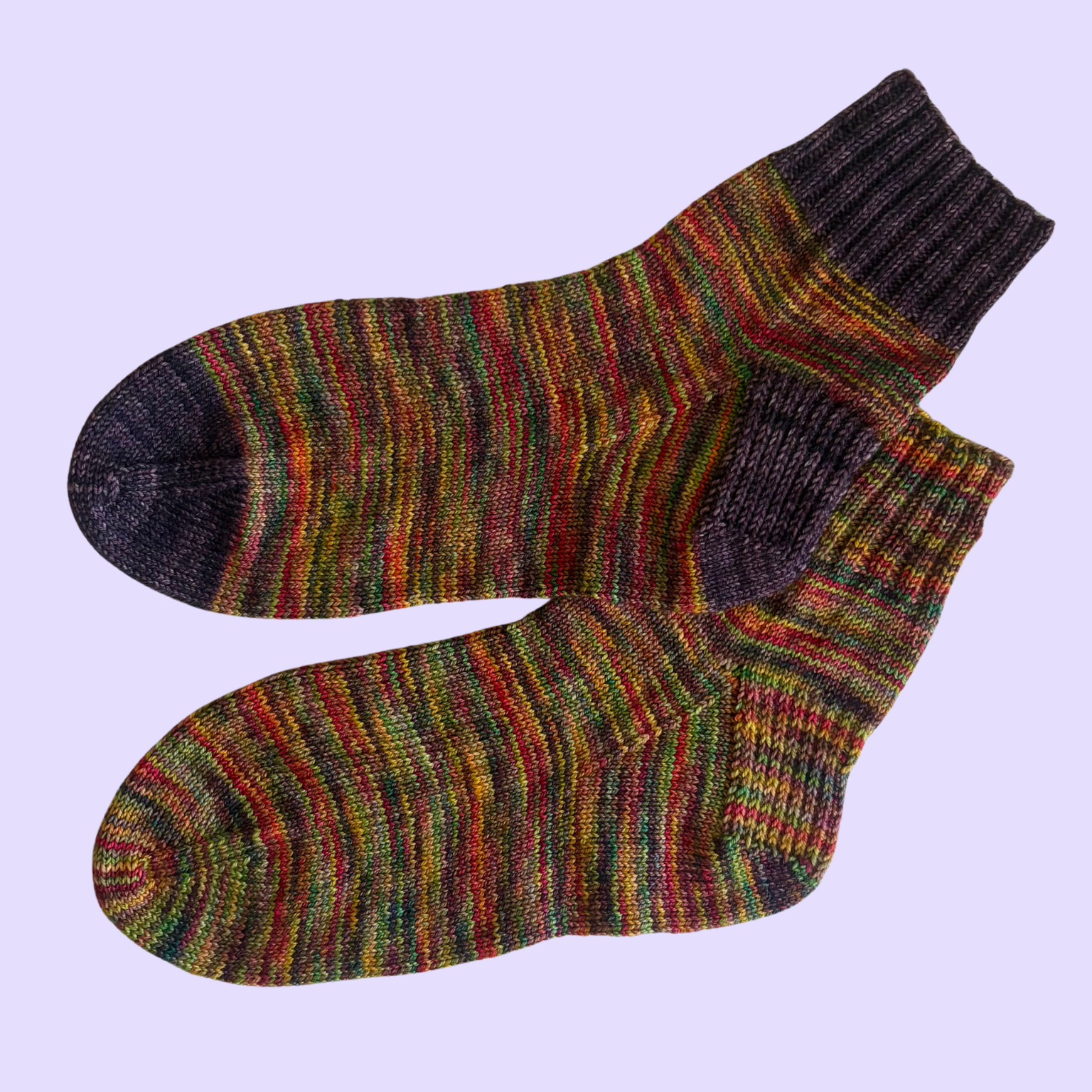 A pair of colorful knit socks on a lavender background.
