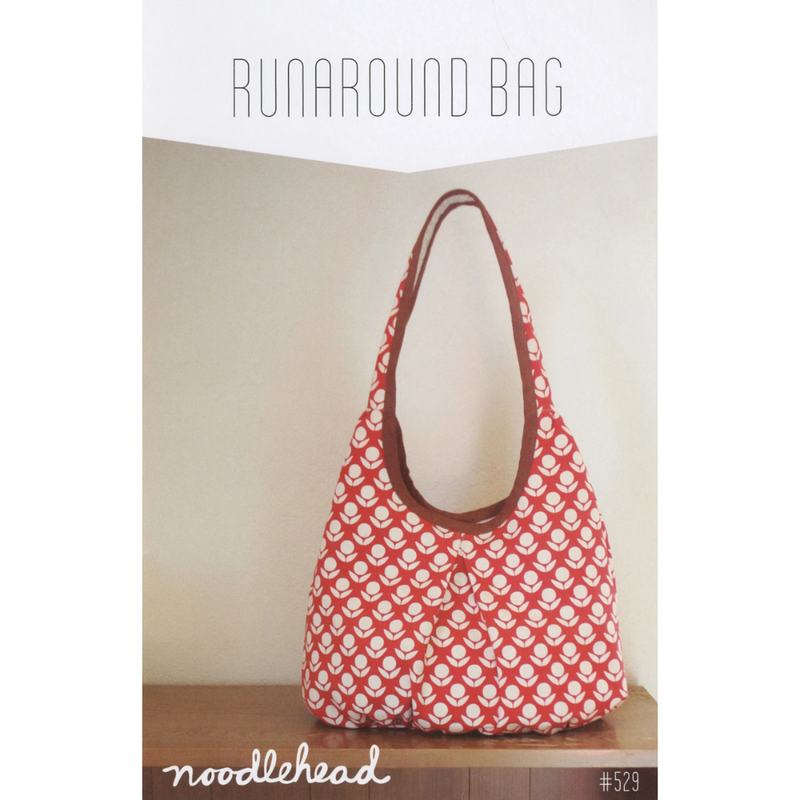Red and white patterned bag with brown handle on a wooden surface, against a plain background.