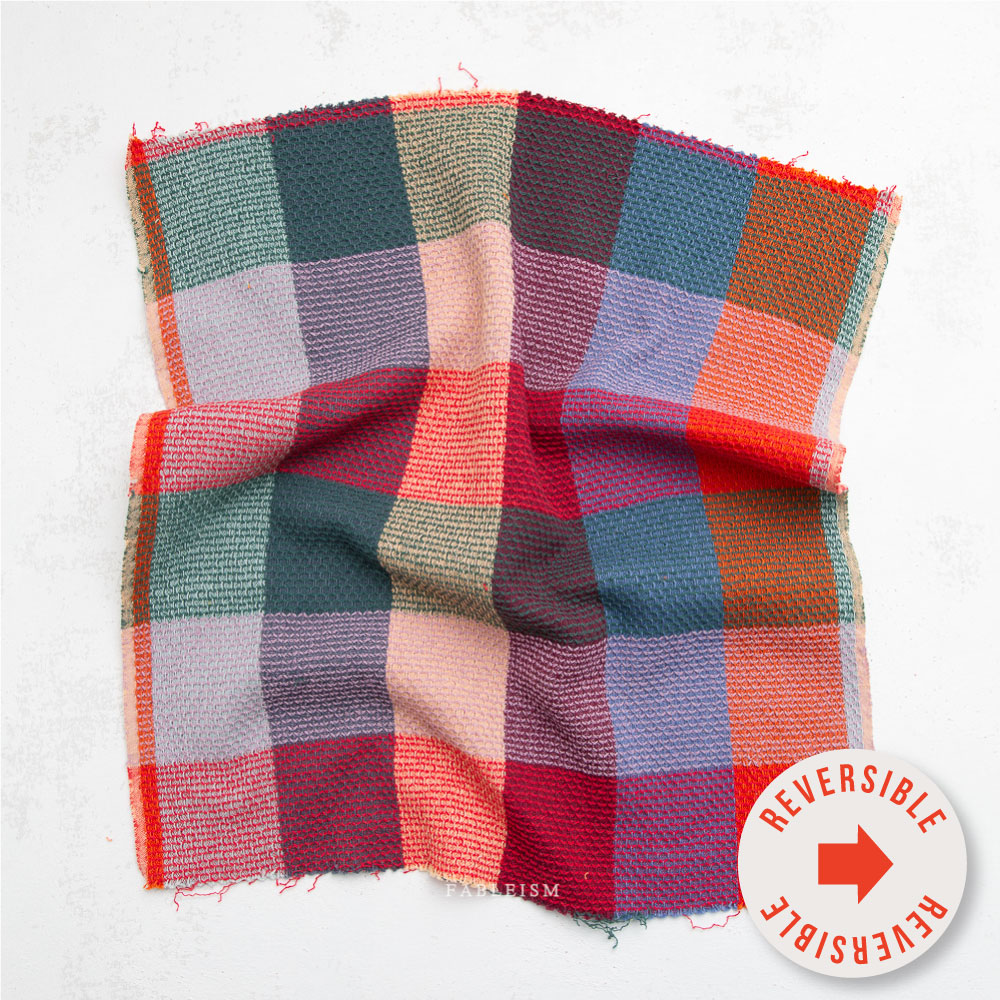 Textured fabric in a red and blue checkered pattern. Sticker in front says "reversible".